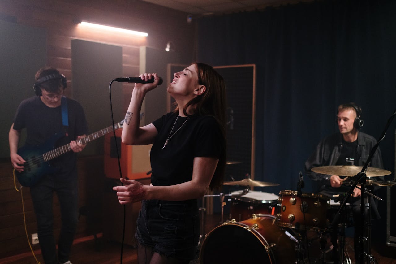 A vibrant indie music band rehearsing indoors with a singer, guitarist, and drummer.